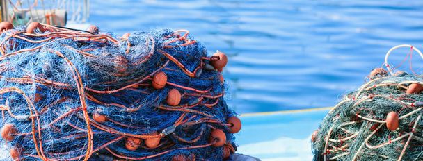 Stapel von Fischernetzen auf blauem Meereswasser Hintergrund. Hafen Marsaxlokk, Malta - Foto, Bild