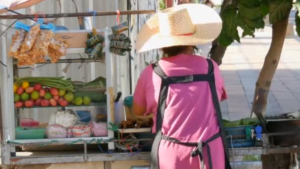 Mujer tailandesa vende comida callejera tailandesa en un carro portátil. Platos exóticos asiáticos
 - Imágenes, Vídeo