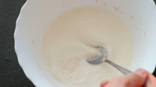 Mixing the yeast with the milk with spoon closeup. Yeast dissolves in milk. Preparation of yeast dough. - Πλάνα, βίντεο