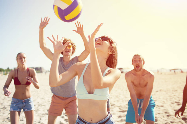 Groep vrienden spelen op beachvolleybal op het strand - Foto, afbeelding