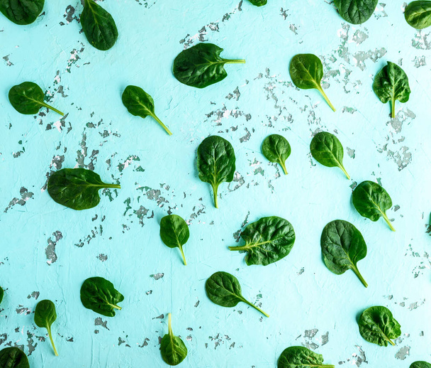 raw spinach leaves are chaotically scattered on a light green su - Photo, Image