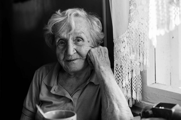 Portrait of elderly woman sitting at the table. - Foto, Imagen