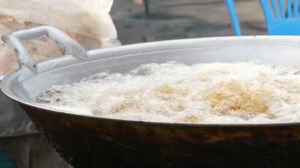 Pouliční jídlo v Thajsku a Asii. Velké varné DPH, v němž žena ruku kuchaře a dát kousky kuřete. Kuřecí obalované vaří ve velkém pánev - Záběry, video