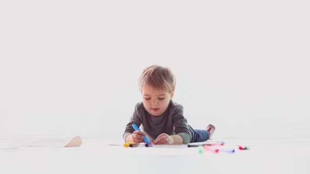 μικρό αγόρι εφιστά χρωματιστά μολύβια σε χαρτί - Πλάνα, βίντεο