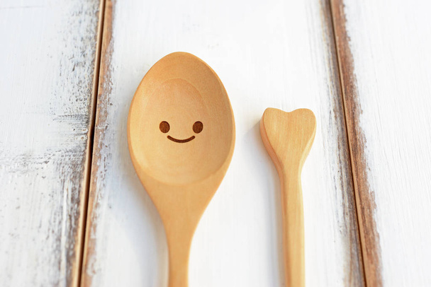 Happy wooden spoon with love on white wooden texture of dining table. Concept about love and relationship. - Fotografie, Obrázek