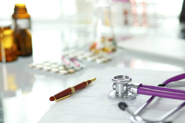 bir doktor ofisi ile bir stetoskop ön planda ve arka planda hapları bir şişeyle Resepsiyon closeup - Fotoğraf, Görsel