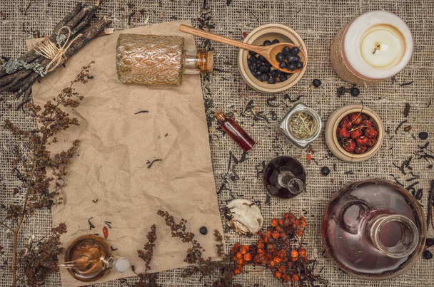 Herbal medicine concept background. Alternative medicine. Dry curative herbs and wild berry essential oil and blank crumpled paper page sheet (recipe, doctor prescription) on burlap sackcloth background with copy space. - Foto, immagini