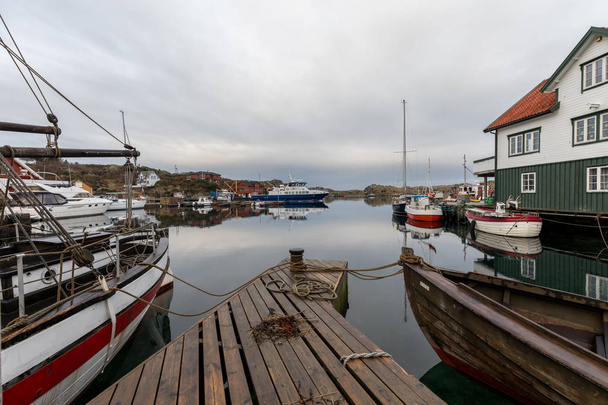 Rovaer in Haugesund, Norway - januray 11, 2018: The Rovaerfjord ferry leaving the Rovaer archipelago in Haugesund. Wooden pier, boats, houses and boat houses by the sea. - Φωτογραφία, εικόνα