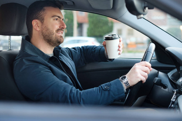 Man drinking coffee while driving the car - Foto, imagen