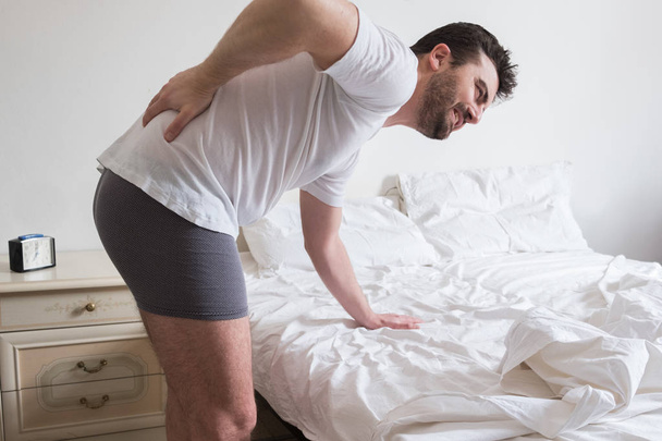 Mann wacht morgens auf und leidet unter Rückenschmerzen - Foto, Bild