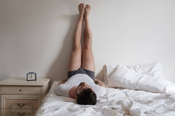 Man doet stretching in het bed voor rugpijn. - Foto, afbeelding