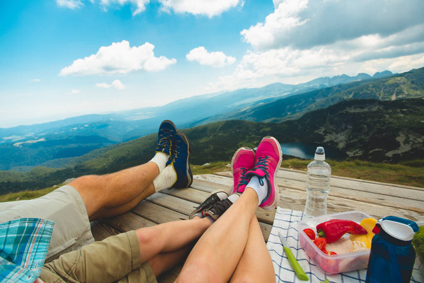 Legs of traveler family sitting on wooden platform high in the mountain. Freedom concept. picnic in nature. Rila mountain in Bulgaria - Photo, Image