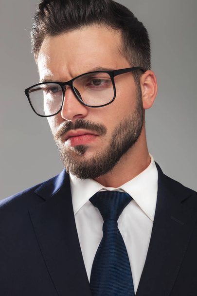 atraktivní vážný podnikatel s brýlemi při pohledu na stranu - Fotografie, Obrázek