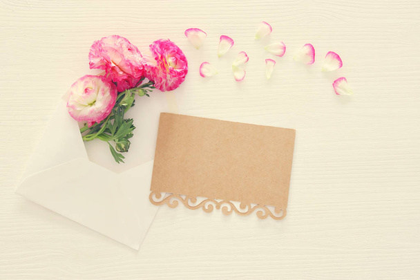 Image of envelope with delicate pastel pink beautiful flowers arrangement over white wooden background. Flat lay, top view. Vintage filtered. - Photo, image