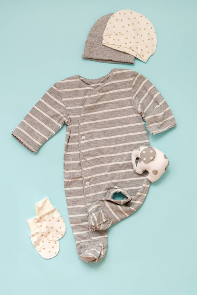 conjunto de roupas de bebê para recém-nascidos em um fundo azul para uma menina ou um menino: um corpo com uma manga longa listrada, uma seleção de chapéus e mitenes. coleção primavera-verão
 - Foto, Imagem