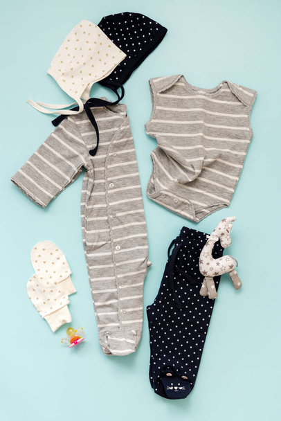 set of children's clothes for a newborn boy and girl on a blue background: a body to choose from, a cap to choose from, trousers and mittens for protection. Collection spring-summer - Fotoğraf, Görsel