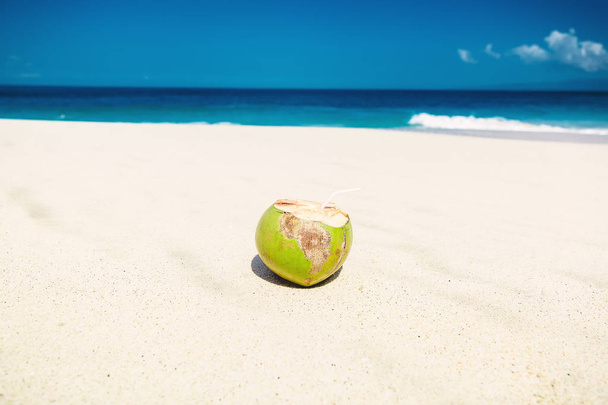 Coconut cocktail on sandy beach with wavy sea on background - Photo, Image