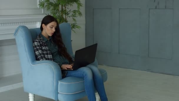 Elegant woman in armchair chatting online via laptop - Materiał filmowy, wideo