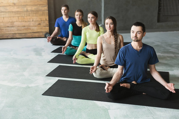 Genç kadın ve erkek yoga sınıfındaki rahatla meditasyon poz - Fotoğraf, Görsel