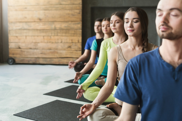 Молодые женщины и мужчины в классе йоги, расслабиться медитации позы
 - Фото, изображение