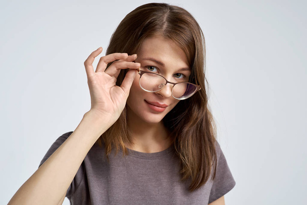 attractive young brunette woman corrects her glasses and looks attentively at the camera. Large horizontal portrait  - Foto, imagen