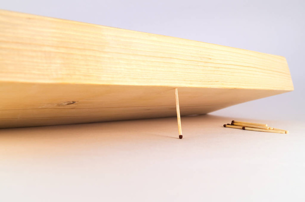 ein dünnes Streichholz verhindert, dass das massive Holzbrett auf die verbleibenden Streichhölzer fällt. - Foto, Bild