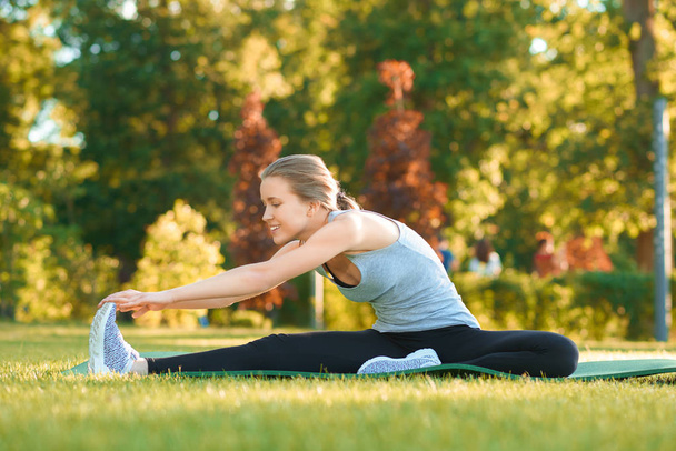 Girl doing stretching on the parks grass. - Zdjęcie, obraz