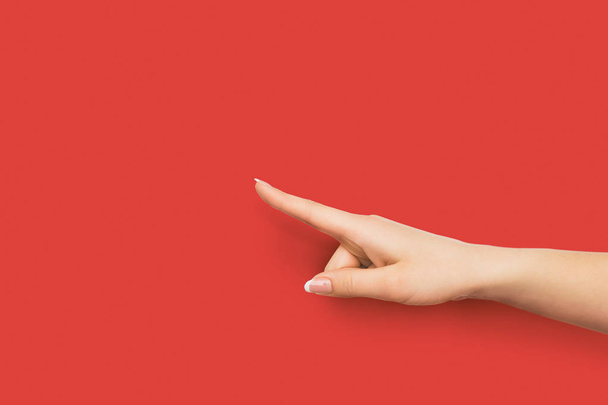 Ręka wskazuje na obiekt z palcem wskazującym na czerwonym tle - Zdjęcie, obraz