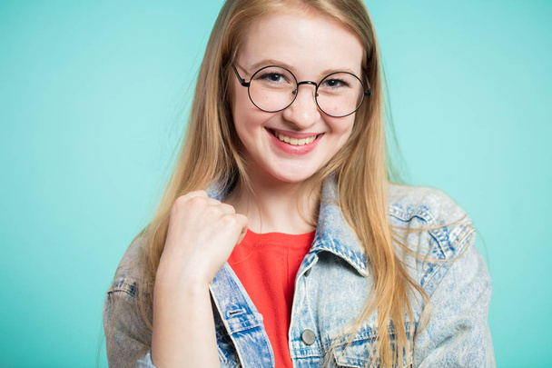Young happy beautiful woman looking at camera. Girl smiling on a blue background - Foto, imagen