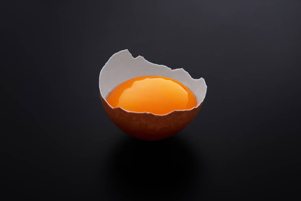 Eigelb in der Eierschale auf schwarzem Hintergrund - Foto, Bild