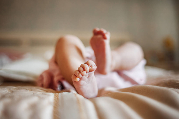 child lays on a soft blanket with bare legs - Φωτογραφία, εικόνα