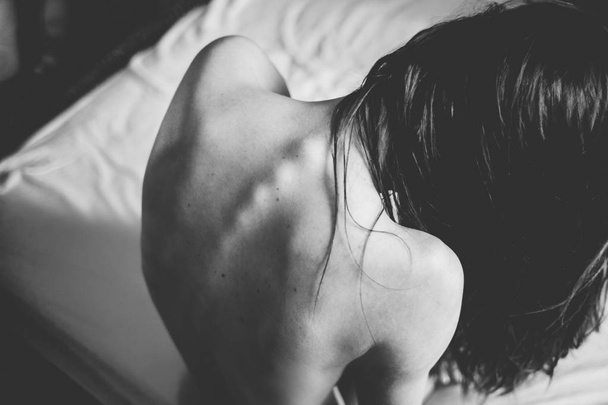 girl with a naked back is sitting on the bed - Fotoğraf, Görsel