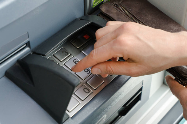 weibliche Hand, die einen sicheren PIN-Code an einem Geldautomaten oder Geldautomaten eingibt, aus nächster Nähe und detailliert - Foto, Bild