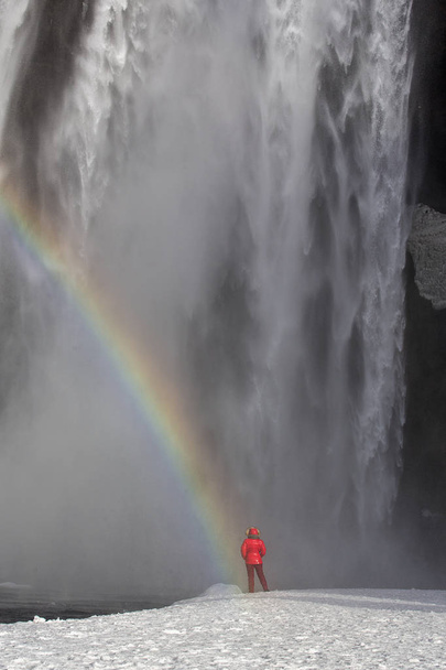 Iceland landscape photo of brave girl who proudly standing with his arms raised in front of water wall of mighty waterfall - Фото, зображення