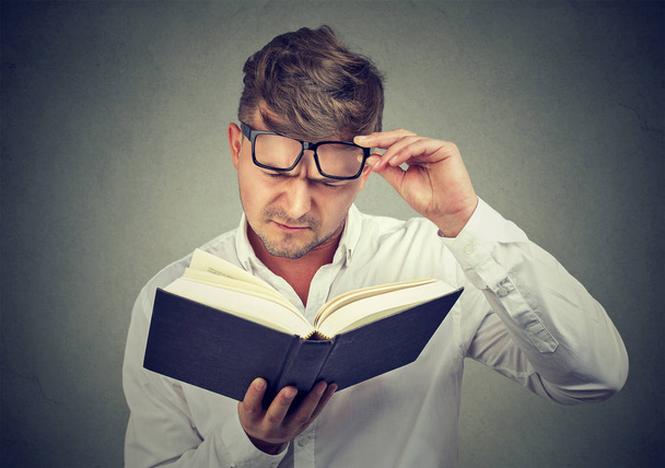 Frowning man having problems with reading - Photo, Image