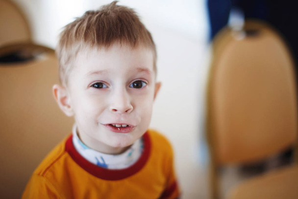 ein kleiner blonder Junge mit großen dunklen Augen in einem braunen Pullover - Foto, Bild
