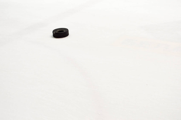 Black rubber small tire for training a game of hockey on the white ice of the hockey arena - Photo, Image