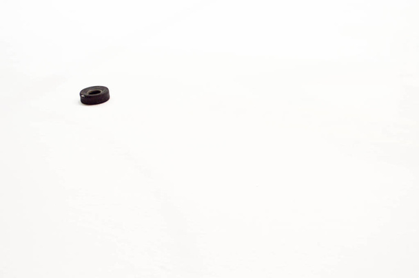 Черная резиновая маленькая шина для тренировки игры в хоккей на белом льду хоккейной арены
 - Фото, изображение