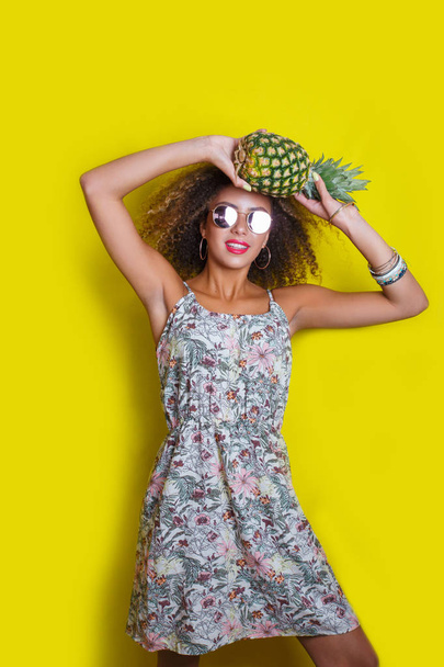 Fashion summer portrait afro american woman in sunglasses and pineapple over yellow background - Foto, Bild