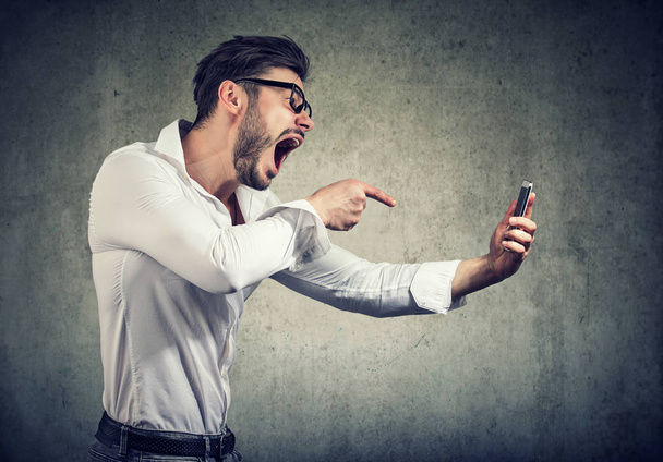 Angry man shouting at phone in hands - Fotó, kép