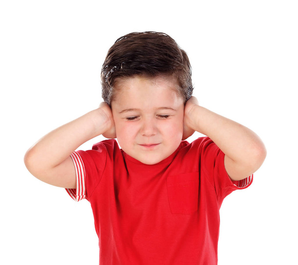 schattige jongen in rode t-shirt die betrekking hebben op zijn oren geïsoleerd op witte achtergrond - Foto, afbeelding