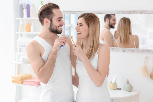 Young couple brushing teeth together in bathroom - Fotó, kép