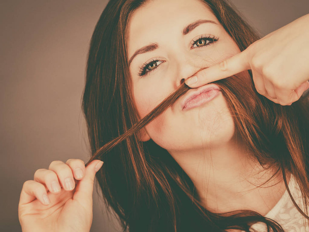 Woman having fun with her hair making moustache - Фото, зображення