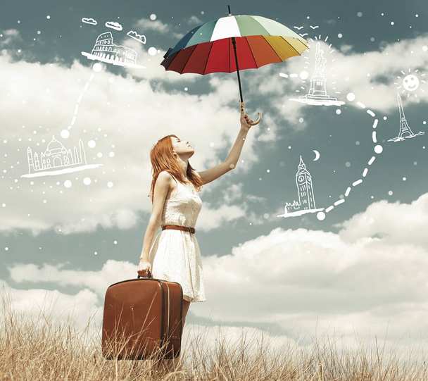 Красивая рыжая девушка с зонтиком и чемоданом на открытом воздухе
. - Фото, изображение
