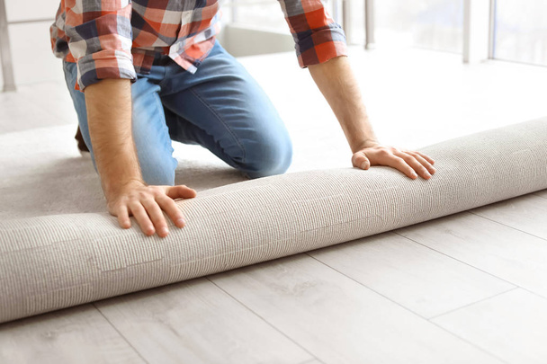 Man rolling out new carpet flooring in room - Foto, Imagem