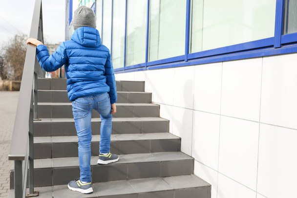 Lonely little boy on stairs outdoors. Autism concept - Foto, afbeelding