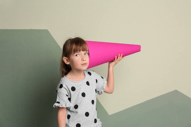 Cute little girl with paper megaphone on color background - Photo, Image