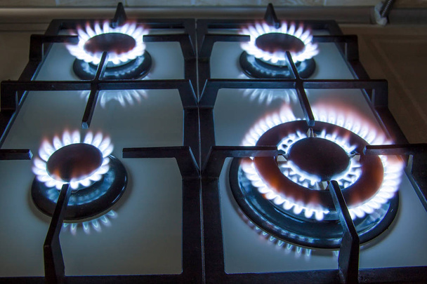 Gas kitchen stove with burning blue flame in dark - Photo, Image
