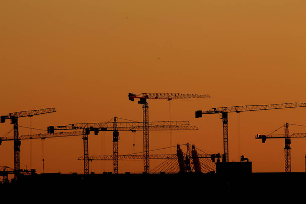 silhouettes of tower cranes against the background of the setting sun - Photo, Image