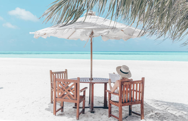 Reizen serie. Malediven eilanden. meisje is ontspannen op het strand en lezing boek - Foto, afbeelding